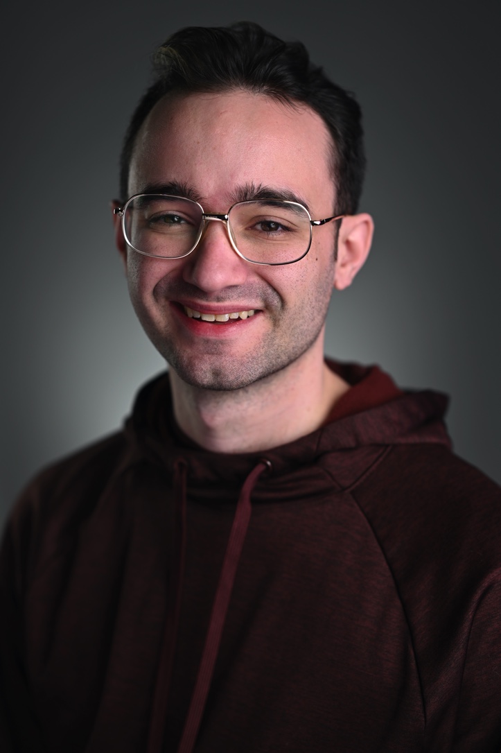 Benji Arrigo 2023 Headshot. Red Hoodie & short hair.